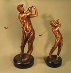 This is a image of two bronze colored golfers in a back swing, standing on black round bases.