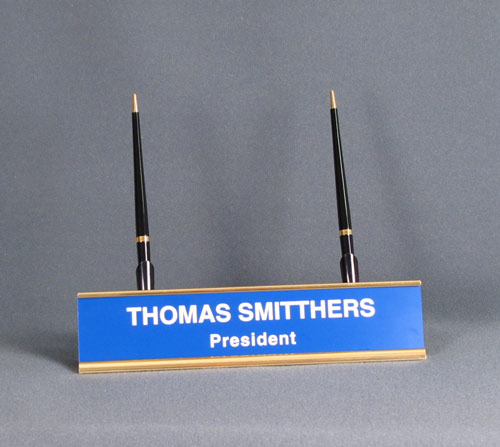 This is a image of a gold tone desk name plate with a plastic engraved insert and two pens